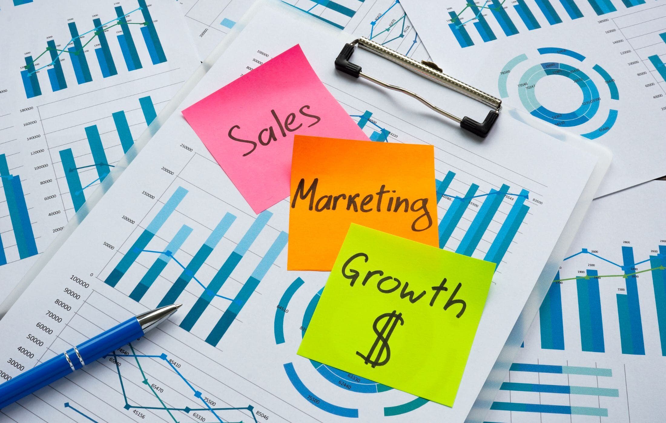 Sales, marketing, and growth notes beside printed charts.